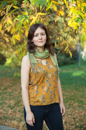 Young woman in yellow autumn park wearing a scarf