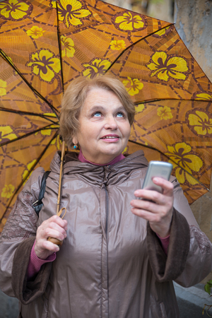 Happy senior Russian woman checking the weatherの写真素材