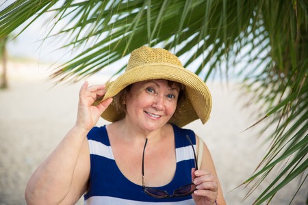 Smiling Senior woman under the palm treesの写真素材