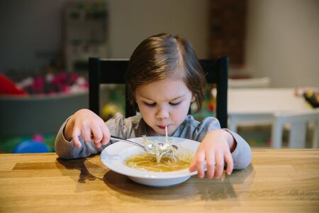 Little girl with a bowl of pasta soupの写真素材