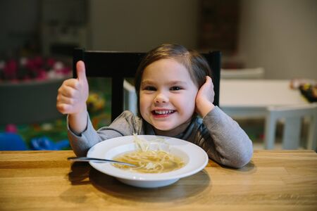Little girl with a bowl of pasta soupの写真素材