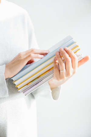 Female hangs gently holding pile of booksの写真素材