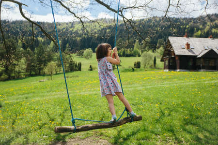 Little girl in green village. Old wooden country house on backgroundの写真素材