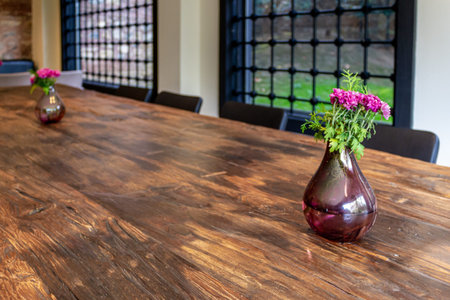 Vase and bouquet of flowers on brown wood table. Home decoration design. Iron barred window