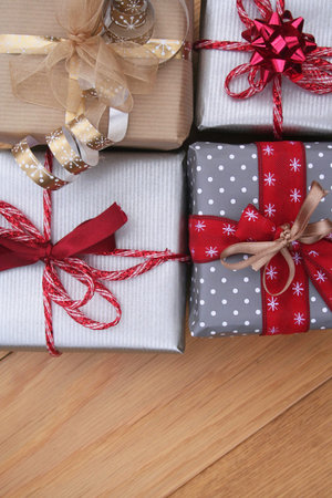 Silver, red, golden and brown Christmas gift boxes on a wooden table.