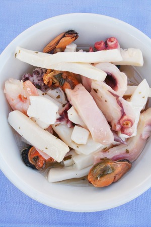 Sea food or sea fruit in a blue napkin on wooden background. Squid, mussels, shrimps and octopus.の写真素材