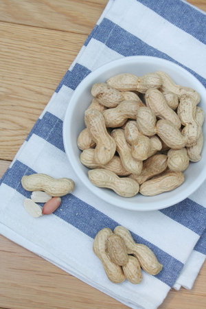 Peanuts in nutshell in a bowl on wooden table