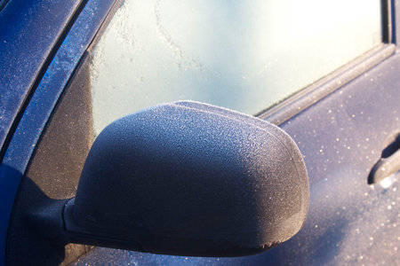 Blue car covered by frost on winter season. Side view of the car in selective focus.の写真素材