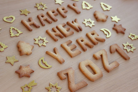 Happy New year cookies. Baked cookie letters on wooden table with shiny decorationsの写真素材