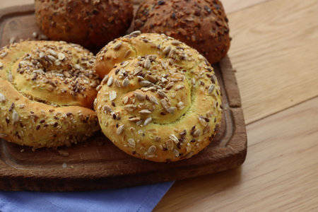 Wheat breads with mixed seeds on a chopping board on wooden table