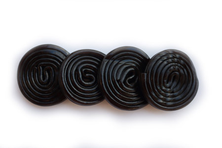 Round black licorice wheels in a row isolated on white backgroundの写真素材