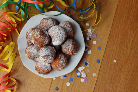 Traditional italian Fritters called Frittelle on a plate with Confetti and Carnival decorations on wooden tableの写真素材