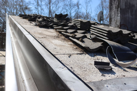 Removing Gray cement roofing tiles damaged by weather on top of a house in Italy