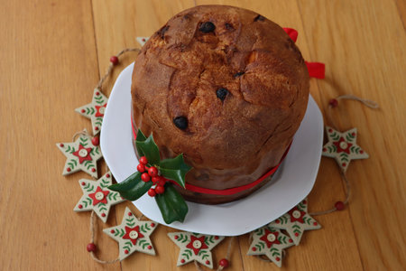 Traditional italian Christmas cake called  Panettone with red ribbon and Holly branch with red...