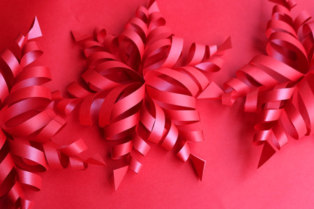 Festive red background for Christmas with red snowflake made of paper on selective focus with copy spaceの写真素材