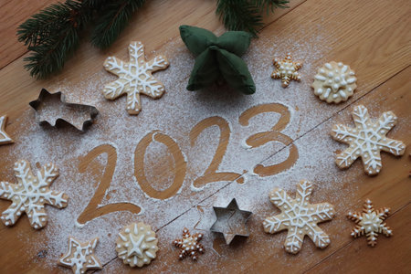 Top view of numbers 2023 written on flour sprinkled on wooden table with branches of pine tree and gingerbread cookies cookies. Merry Christmas and Happy New Year 2023の写真素材