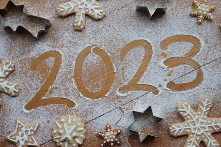 Top view of numbers 2023 written on flour sprinkled on wooden table with Ã¬ gingerbread cookies cookies. Merry Christmas and Happy New Year 2023の写真素材