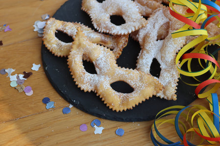 Traditional sweet crisp pastry deep-fried in shape of Carnival mask on a black slate stone plate. Chiacchere or crostoli, bugie, cenci with copy spaceの写真素材