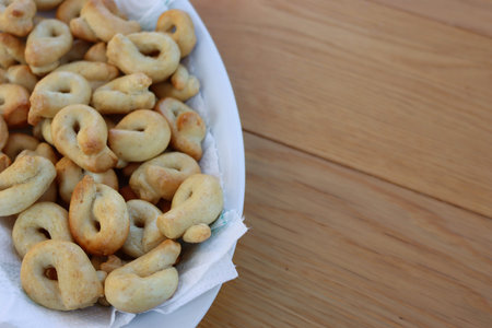 Traditional italian snack from Puglia called Taralli on a white bowl on wooden table. Selective...