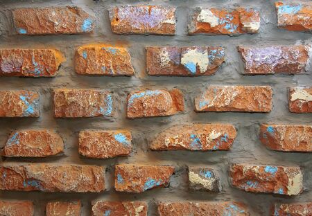 Photo background wall of brown old decorative brick with scratches, scuffs, cracks.の写真素材