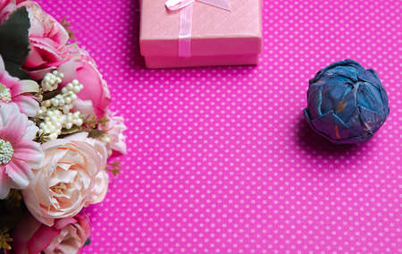 A flat lay photo of a bouquet of flowers, a gift in the form of a box and accessories on a pink background top view. High quality photoの写真素材