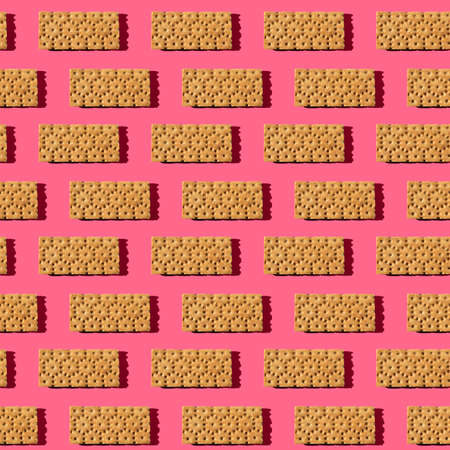 Photo in the form of a seamless pattern. Orange color crisps for healthy food with shadows on a colored pink background.の写真素材