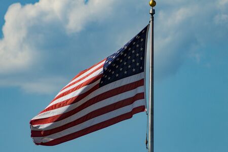 United States flag with blue sky and cloudsの写真素材
