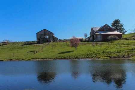 Two barns on a hill overlooking a pondの写真素材