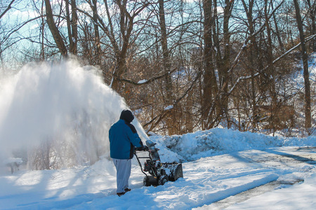 Adult male snow blowing his driveway after a snowfallの写真素材