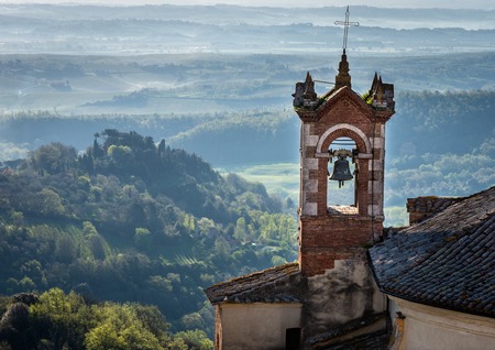 churchsteeple in Montepulcian Italy sunrise fog in hillsの写真素材