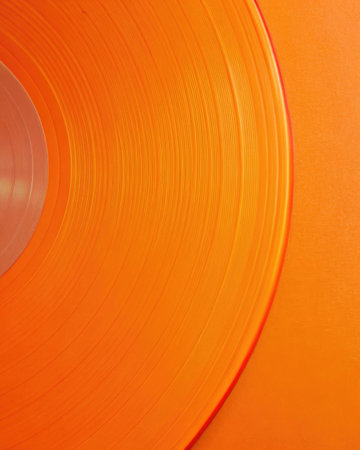 Bright orange vinyl record with detailed grooves.の素材