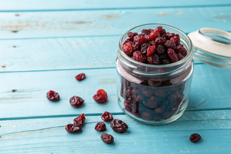 Dried Cranberries in Glass Jar on Rustic Blue Wooden Tableの素材