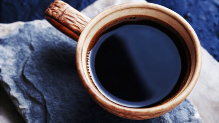 Close-Up of Black Coffee in a Rustic Clay Mug on a Stone Surfaceの素材