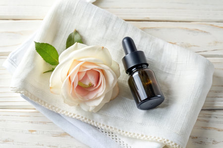 Essential oil with rose flower on white wooden table, top viewの素材