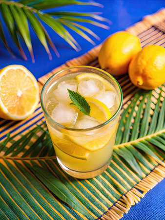 Cocktail with lemon, mint and ice on a blue backgroundの素材