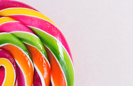 Bright rainbow round lollipop. Isolated on pink background.Copy spaceの写真素材