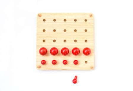 Red pegs board, wood beads on white backgroundの写真素材