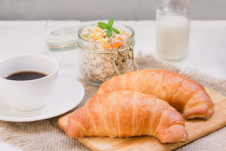 Continental traditional breakfast. Croissant, a cup of coffee and an granola. On a white background, on a canvasの写真素材