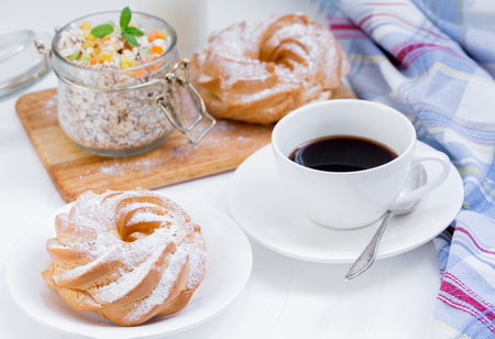 A cup of coffee, a granola, buns on a white background near a striped napkinの写真素材