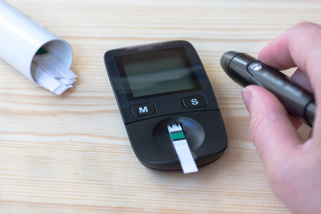 A young woman holds a glucometer in her hands and wants to do a blood test for sugarの写真素材
