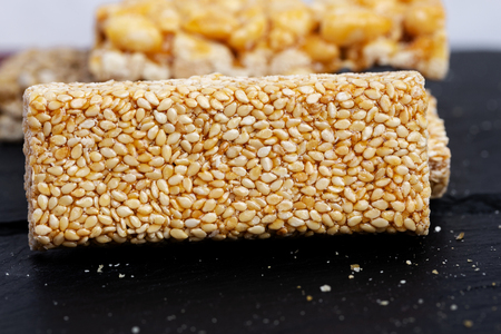 Granola bar. Healthy sweet dessert snack. Sesame, hazelnut, sunflower in honey. Gozinaki is Georgian national food, oriental sweet on black stone background.の写真素材
