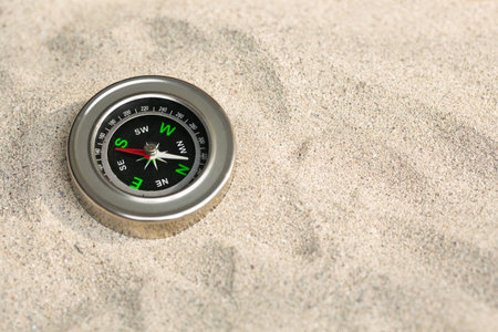 Compass on beige sea sand. Retro navigator when traveling. Background