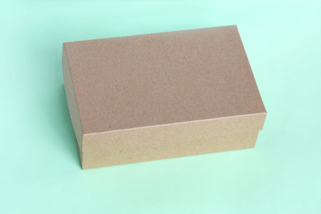 Closed cardboard box on green background.