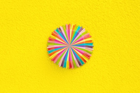 Rainbow colored paper baking cups for muffins and cupcakes on a yellow  minimal creative concept. Space for copyの写真素材