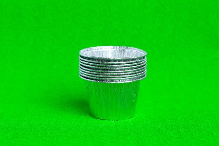 Stack metal baking cups for muffins and cupcakes on a green  minimal creative concept. Space for copyの写真素材