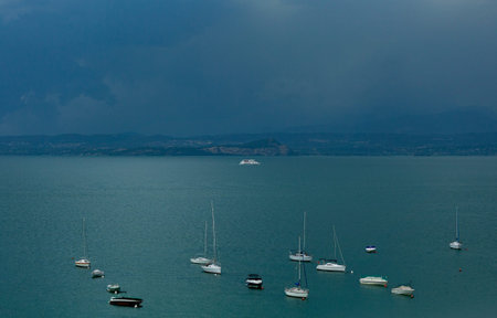 The view from the top to Lake Garda is fabulous. A gloomy sky awaiting a thunderstorm. Ship, boat,...