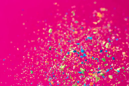 Crumbs of a multicolored chalk fly on a pink background. Joy, Carnival. Game for children