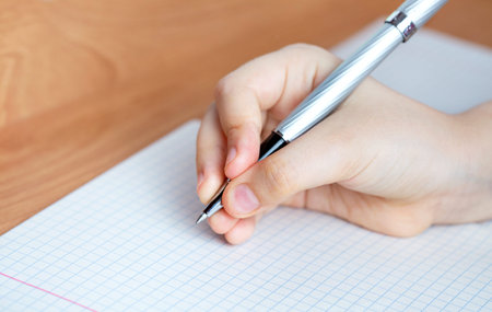 The child writes in a notebook. Space for copy. Focus is on child's hands