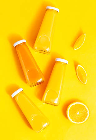 Bottled orange juice and oranges on a yellow background. The concept of a juicy, bright summerの写真素材