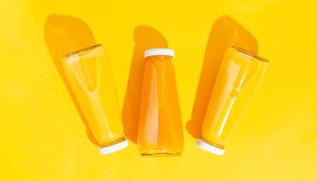 Bottled orange juice and oranges on a yellow background. The concept of a juicy, bright summerの写真素材